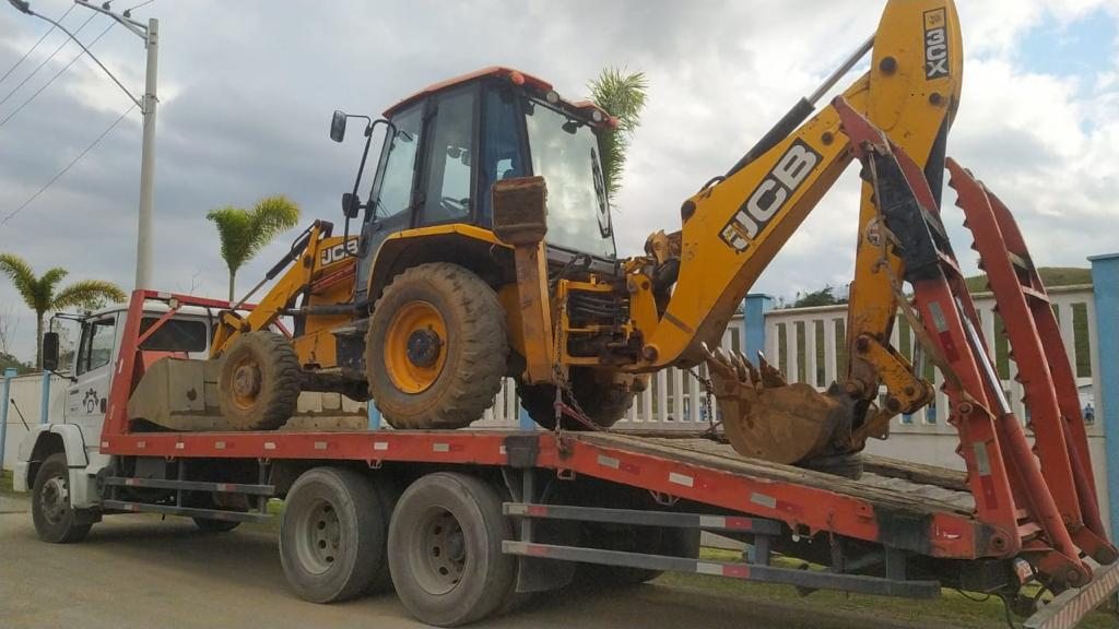 Retroescavadeira sobre caminhão prancha em mobilização para obra
